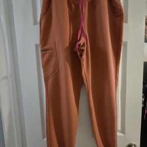 Figs Terracotta Jogger Scrub Pants with Pink Drawstring.
